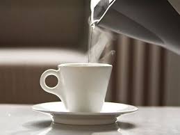 An image of hotwater being poured onto a ceramic cup from a kettle